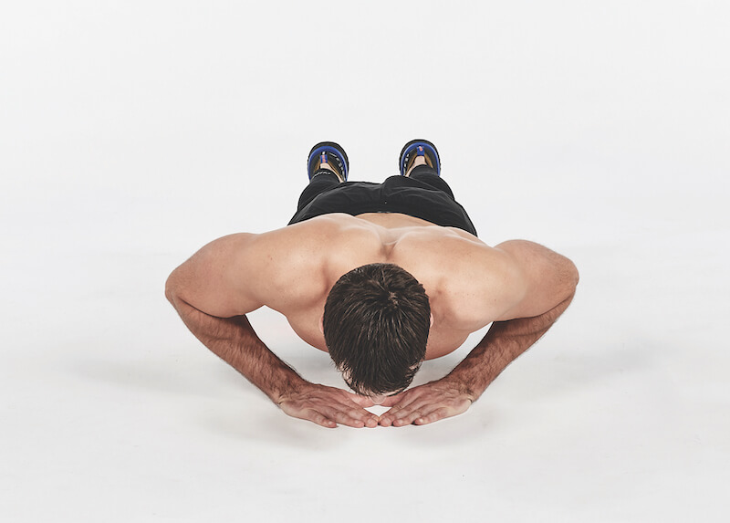 topless man demonstrates how to do diamond push-up exercise