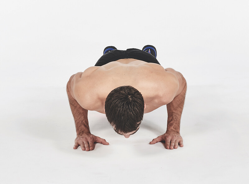 topless man demonstrates push up exercise, one of the best workout finishers