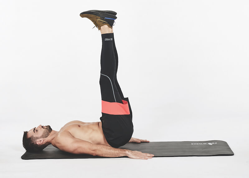 topless man demonstrates how to do leg lift exercise on floor