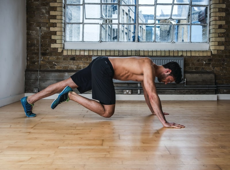 Man performing single-leg knee twist – one of the best plank variations