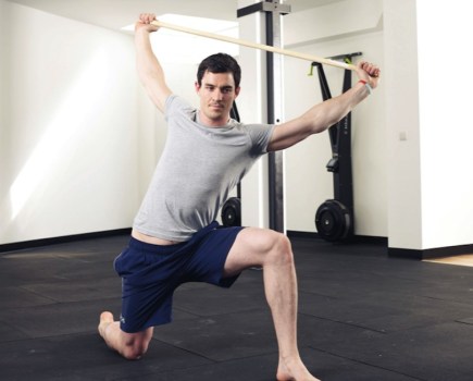 Man performing stretches with a stick