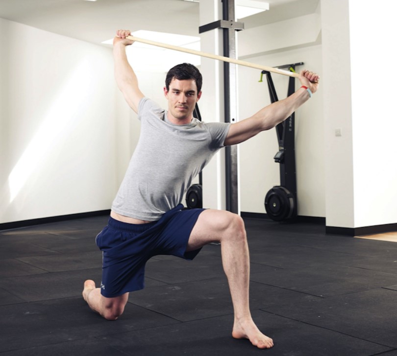 Man performing stretches with a stick