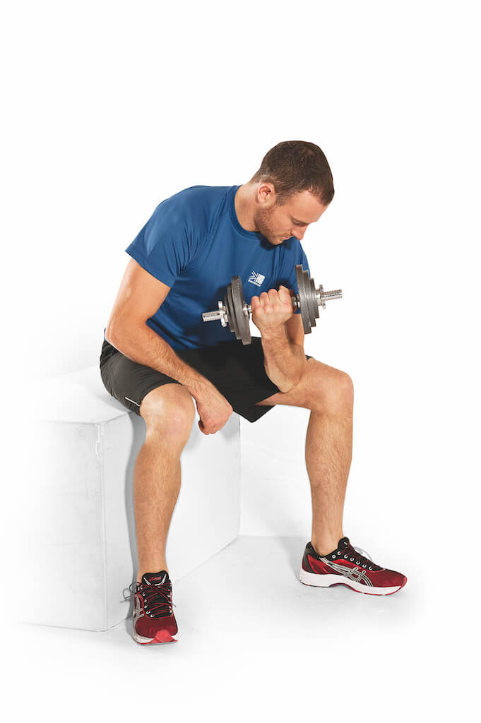 man performing concentration curl as part of an arms workout with dumbbells