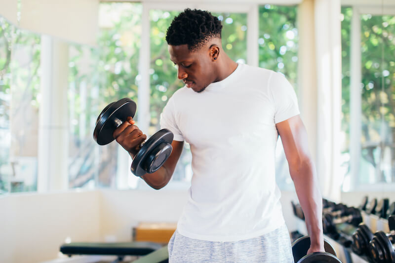 man at home performing dumbbell curls