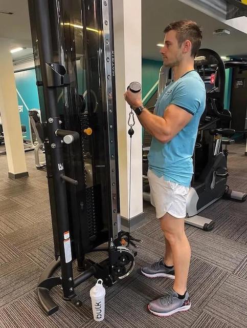 man performing cable curl as part of 30-minute upper-body workout