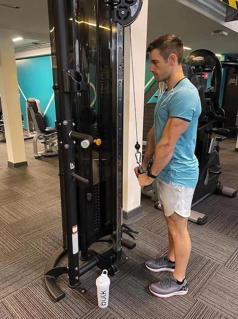 man in turquoise t-shirt performing cable triceps push-down