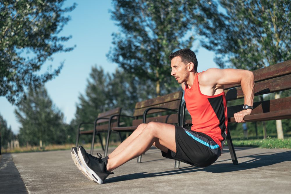 man performing triceps dips on a park bench