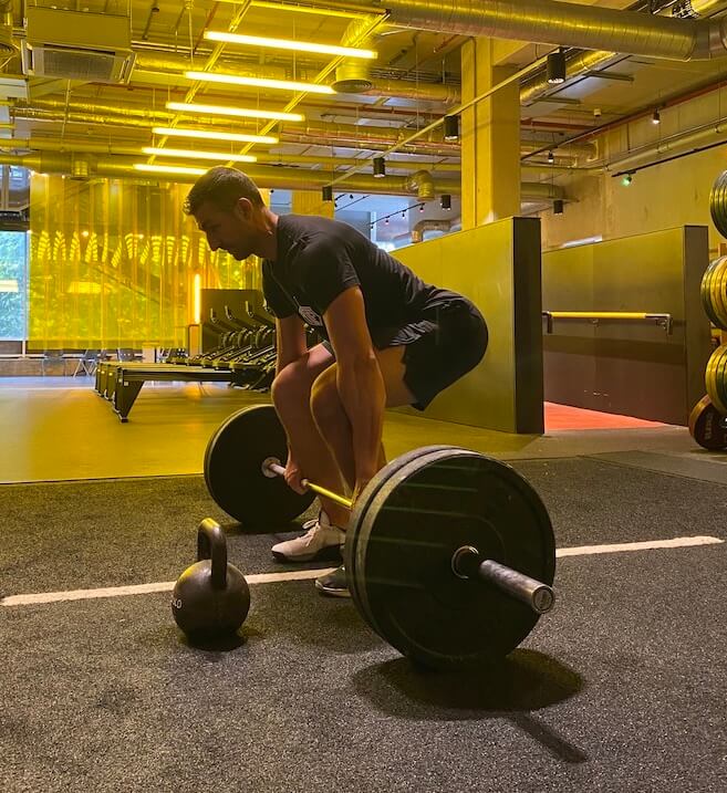 man performing barbell deadlift as part of a full body workout routine