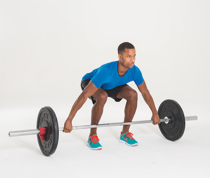 man performing the first stage of a barbell shrug