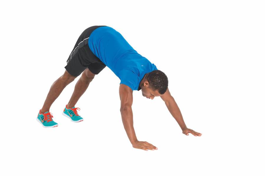 man in blue t-shirt and shorts performing downward dog yoga pose 