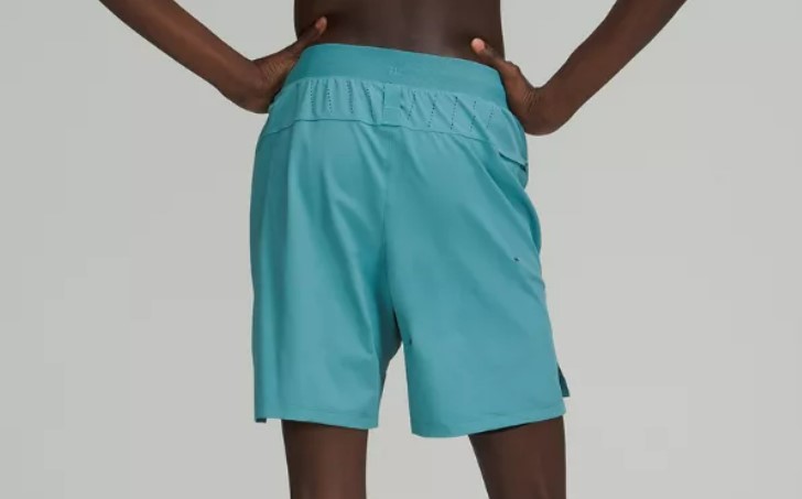 A man from the waist down, from behind, hands on hips, wearing a pair of Lululemon License to Train Lined 7-inch shorts
