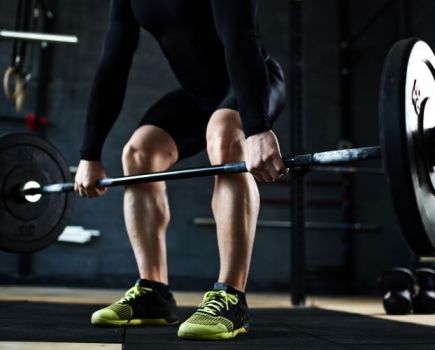 Lower torso of a man lifting a barbell in the gym