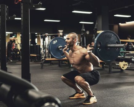 Man in gym performing barbell squat