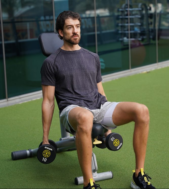 Man sitting performing start of dumbbell hammer curl