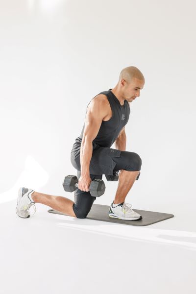 man demonstrates curtsy lunges: holding a dumbell in each hand, he lunges until his knee nears the floor