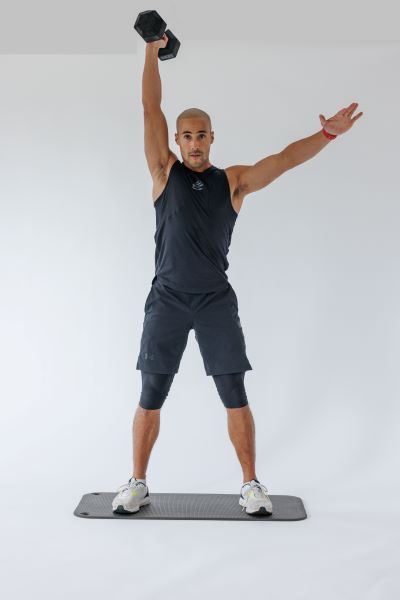 dumbbell single arm snatch demonstration step 2: Drive the dumbbell up explosively using your legs and back keeping a close central line to the body. Once it reaches the level of your hips, drive the dumbbell up with your arm, using that momentum created from the first part of the movement