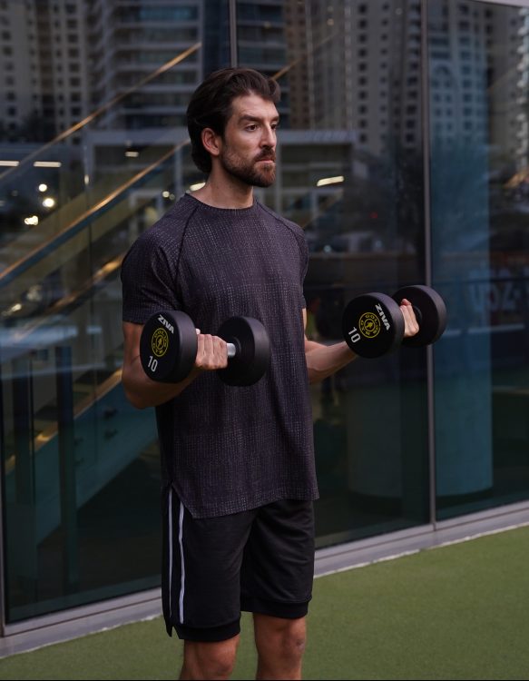 Man standing performing middle of dumbbell 21 curl