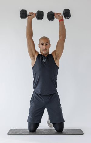 Man performing end of kneeling arnold shoulder press