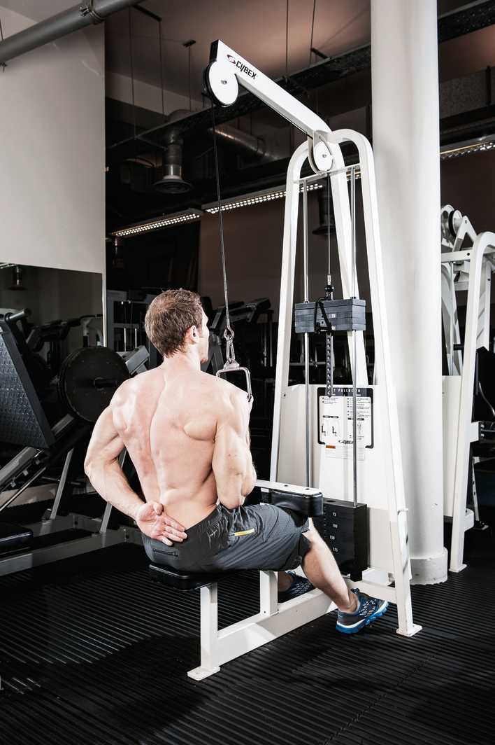 man demonstrates single arm pull down in the gym