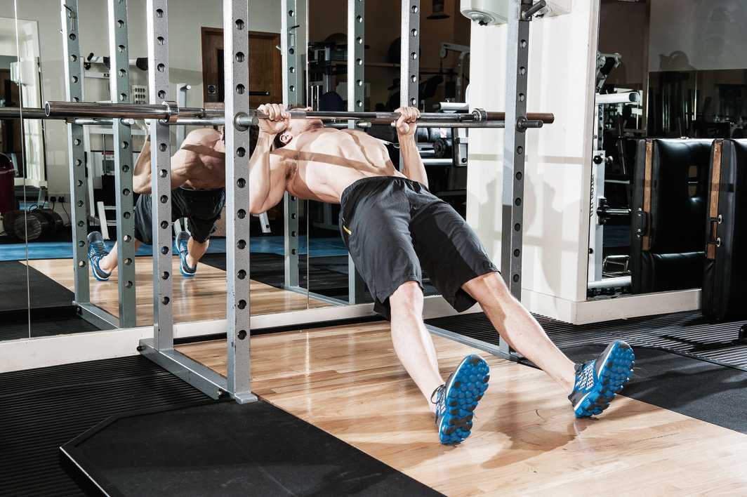 man demonstrates inverted row in gym