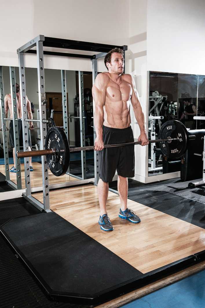 man demonstrates barbell shrug