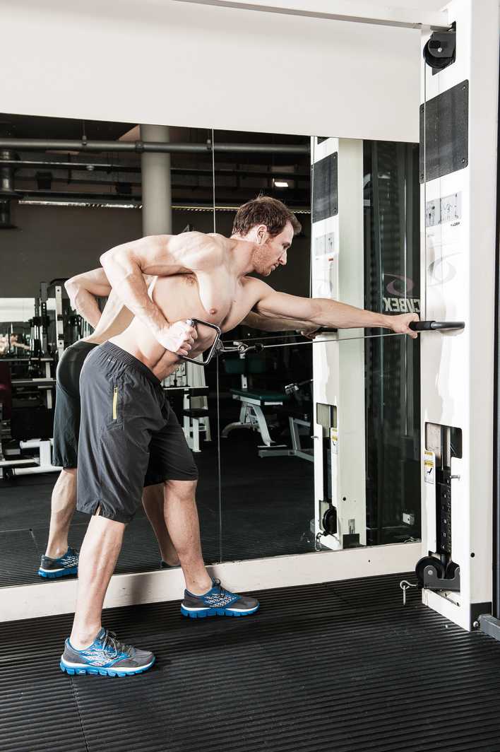 man demonstrates single arm cable row in the gym to build back muscles