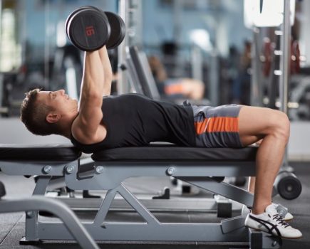 Man performing dumbbell chest workout on a bench