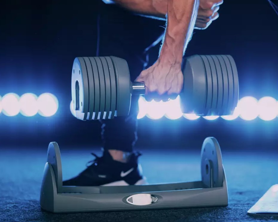A man lifting the JaxJox dumbbell from its docking station