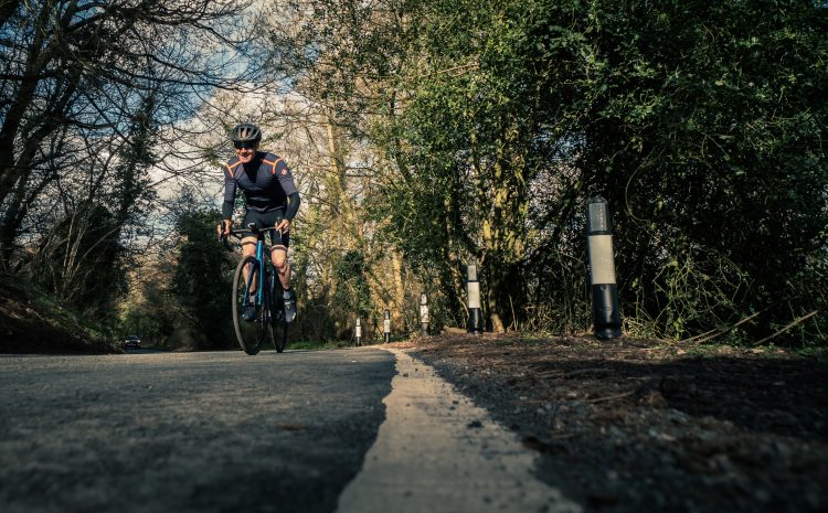 Man climbing a hill on a road bike - improve your cycling fitness