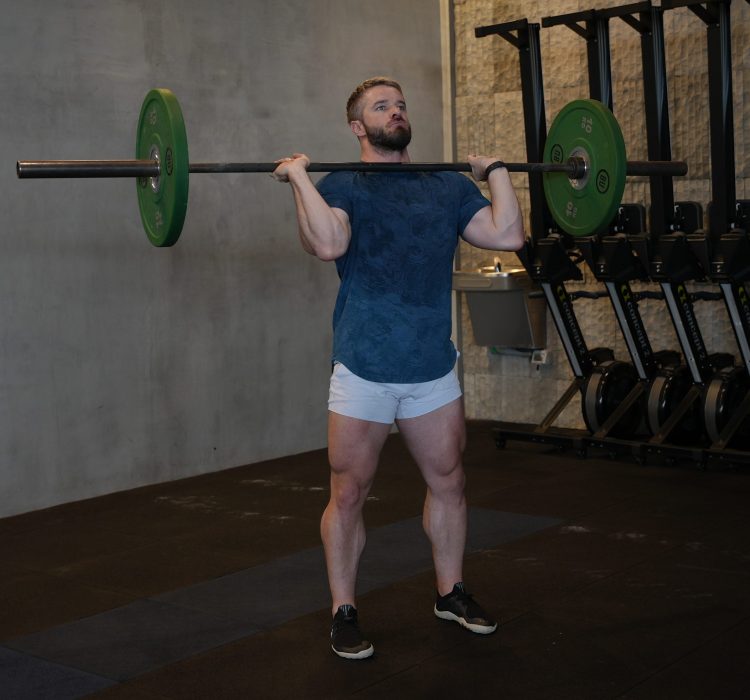 Man performing start of barbell press - best shoulder press variations