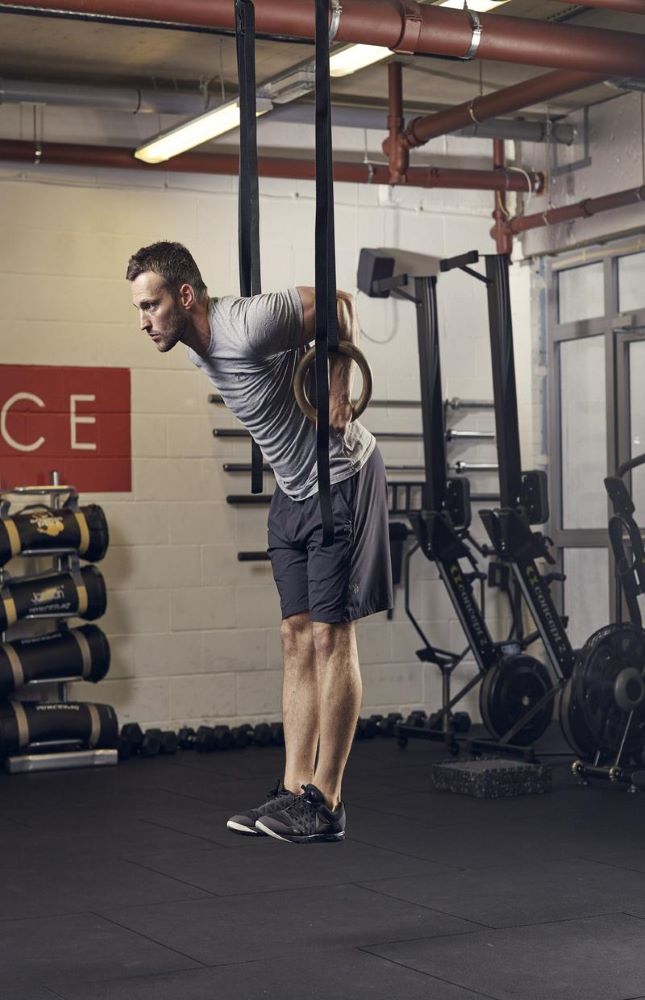 man demonstrating how to do a ring dip in the gym