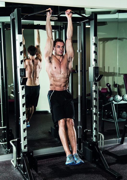 Man in a gym performing a hanging leg raise