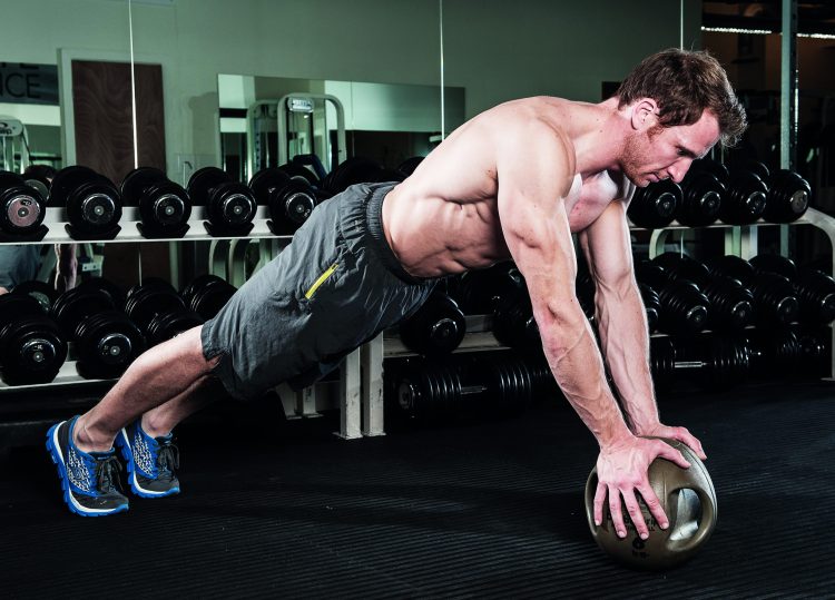 Man perfoming medicine ball press-up in gym - how to grow bigger arm muscles