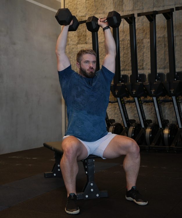 Man performing end of seated dumbbell shoulder press - best shoulder press variations