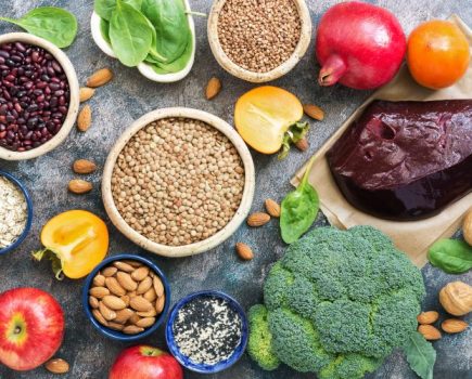 Iron-rich food on a table - including liver, broccoli, apples, nuts and pomegranates