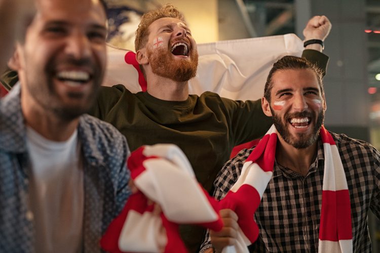 Football fans wearing red and white scarfs celebrating