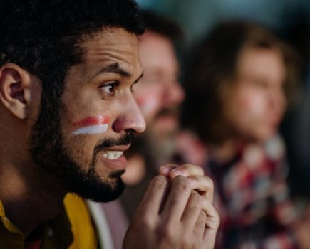 Three anxious football fans watching a game at home