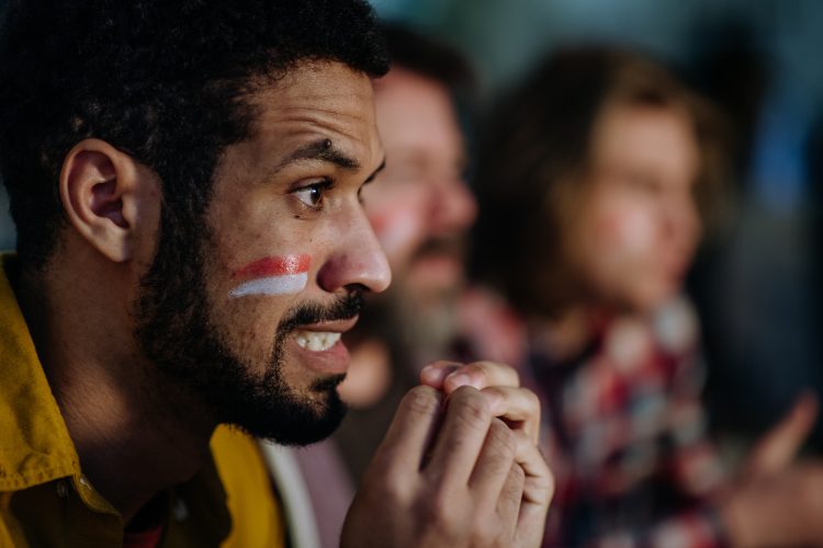 Three anxious football fans watching a game at home