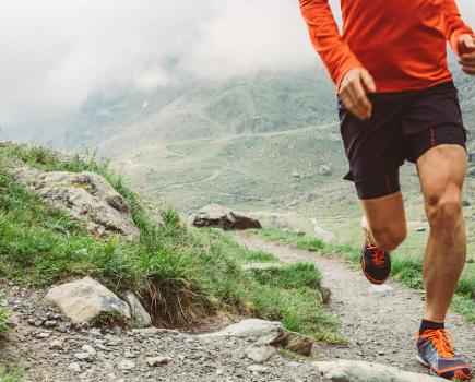 Lower half of man running in the mountains