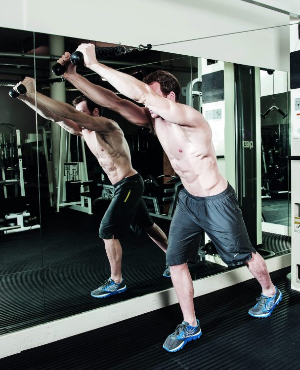 Man performing the end of the standing cable superman - how to build bigger arm muscles