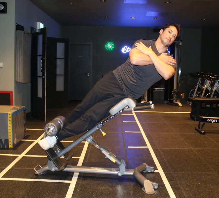 Man performing a 45 degree side bend top position - best lower back exercises