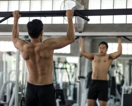 Man in a gym performing bar pull-ups