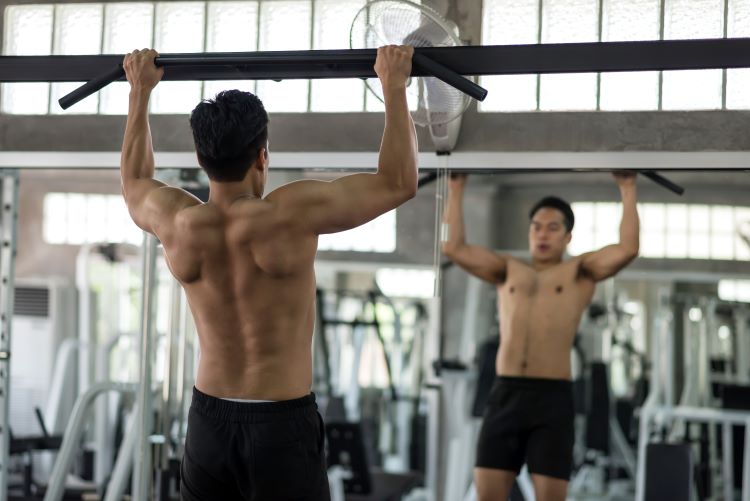 Man in a gym performing bar pull-ups