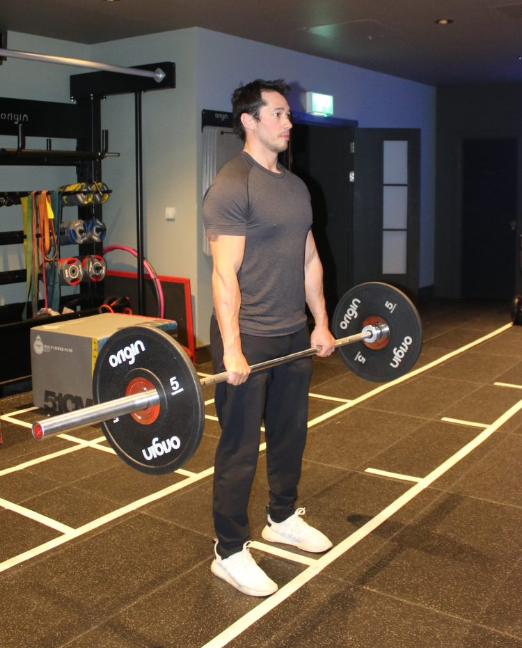 Man performing the end of a conventional deadlift - best lower back exercises