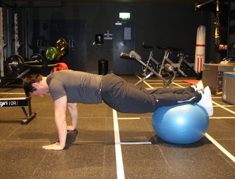 Man performing gym ball frog 