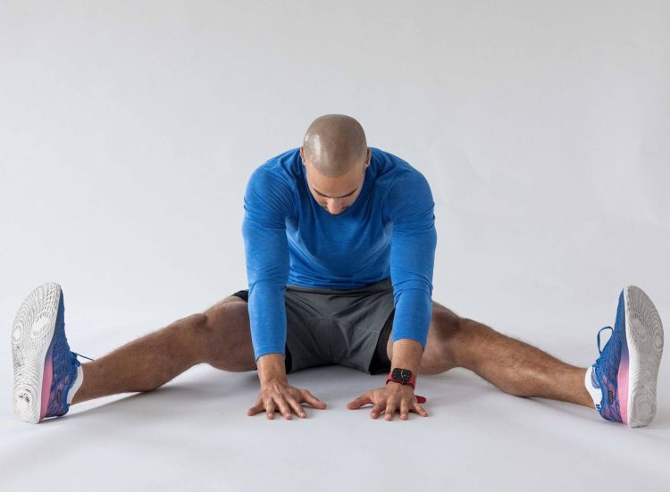 Man performing end of a wide-angle seated forward stretch -