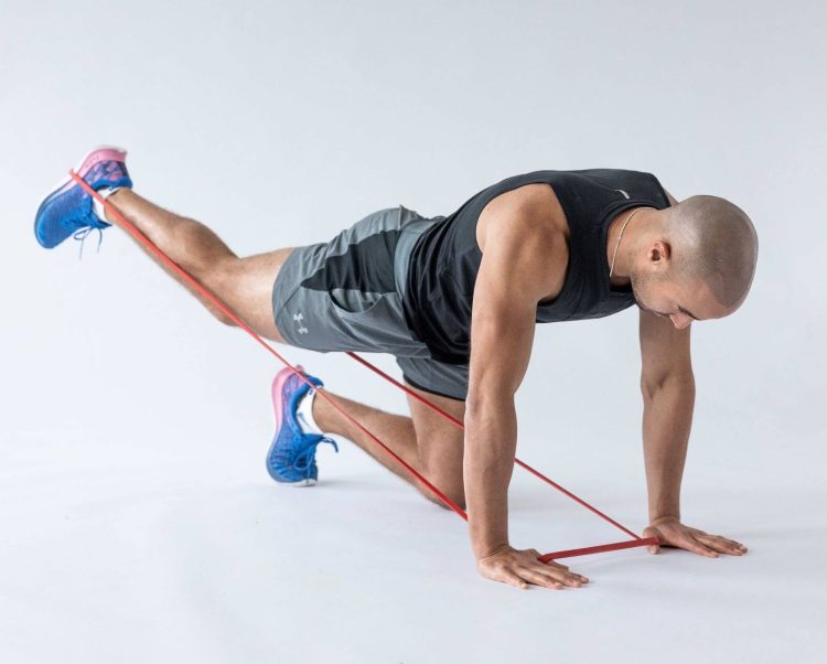 Man performing end of a banded kickback - resistance band leg exercises