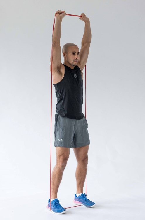 Man performing end of a banded overhead shoulder press - resistance band arm exercises