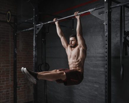 Man holding onto a bar performing abs exercise - best lower abs exercises