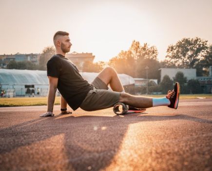 A man outside using a foam roller on his legs